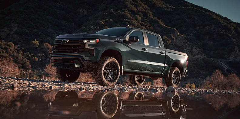 A green 2025 Chevy Silverado 1500 parked in front of a stream of water.