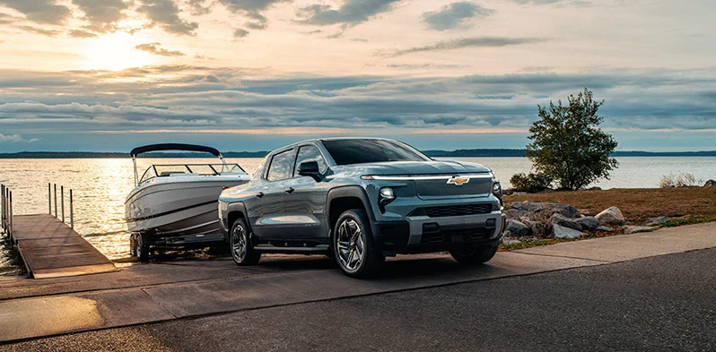 A 2026 Chevrolet Silverado EV backing a boat down a boat ramp.